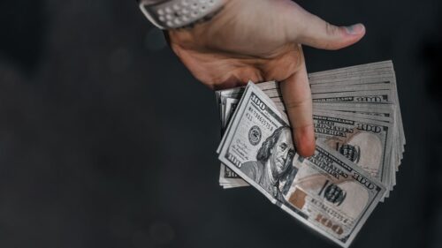 Hand holding dollars in the dark